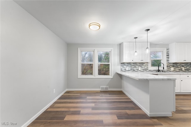 kitchen featuring white cabinets, kitchen peninsula, backsplash, and a wealth of natural light