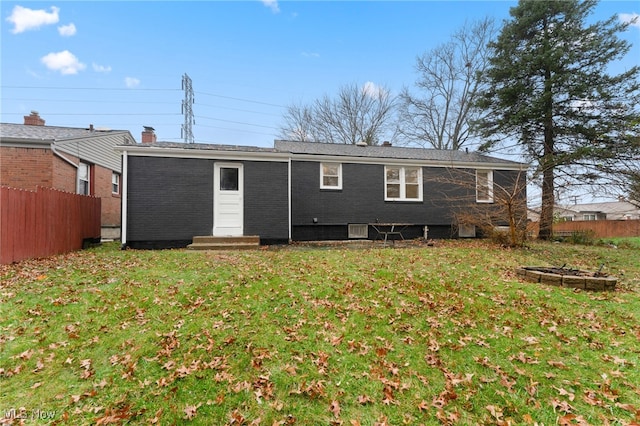 back of house with a lawn and a fire pit