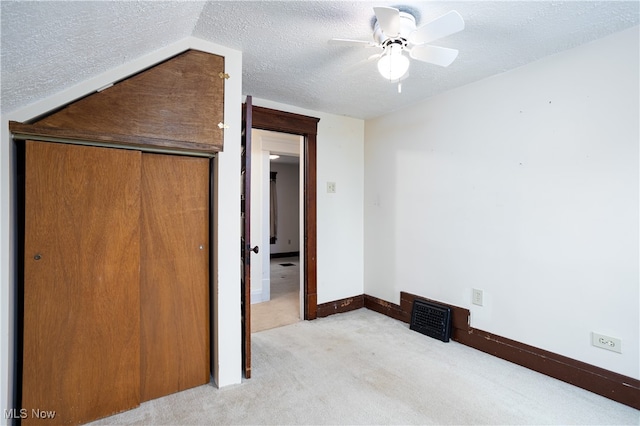 unfurnished bedroom with a closet, a textured ceiling, light colored carpet, and ceiling fan