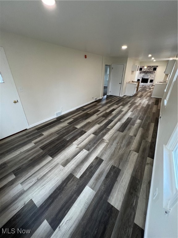 unfurnished living room featuring dark hardwood / wood-style flooring and a brick fireplace