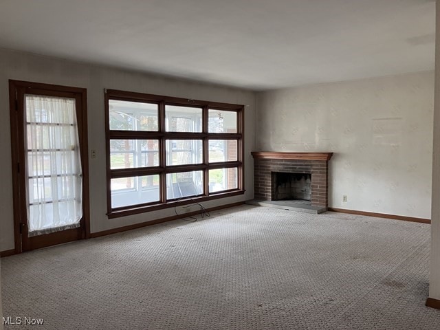 unfurnished living room featuring light carpet and a brick fireplace