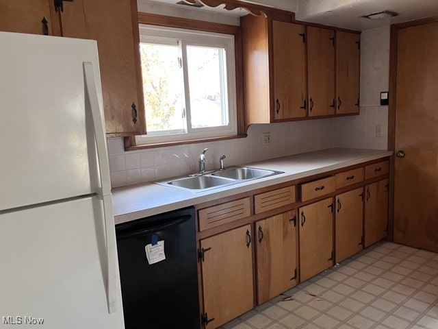 kitchen with black dishwasher, decorative backsplash, white refrigerator, and sink