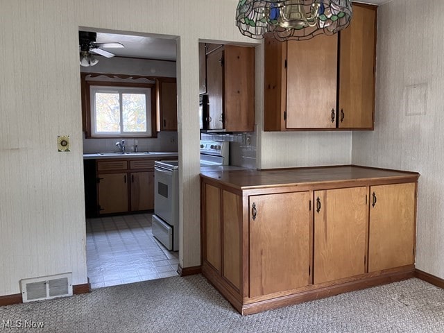 kitchen featuring sink, ceiling fan with notable chandelier, and white electric range