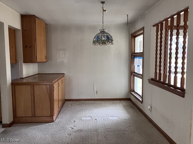 unfurnished dining area featuring a chandelier and light carpet