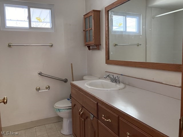 bathroom with tile patterned floors, plenty of natural light, toilet, and vanity