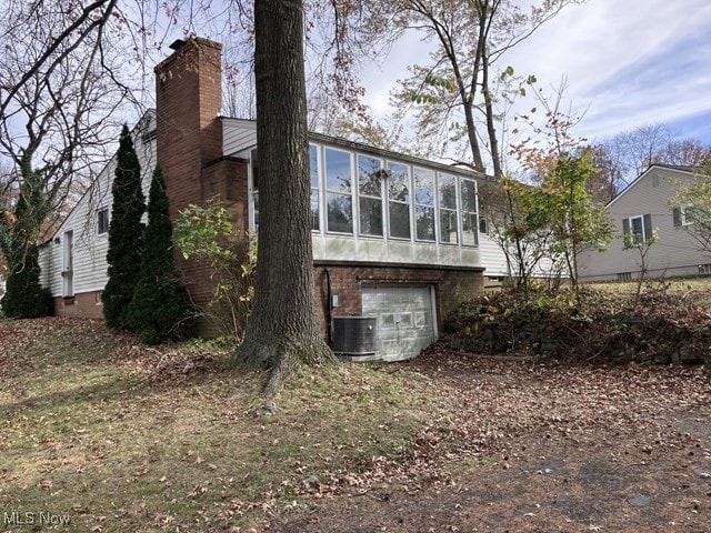 rear view of property with central AC and a sunroom