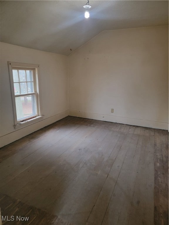 spare room with hardwood / wood-style flooring and vaulted ceiling