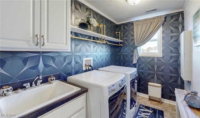 washroom featuring sink, washer and clothes dryer, cabinets, and crown molding