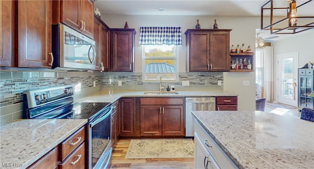 kitchen featuring hanging light fixtures, sink, appliances with stainless steel finishes, tasteful backsplash, and light hardwood / wood-style floors