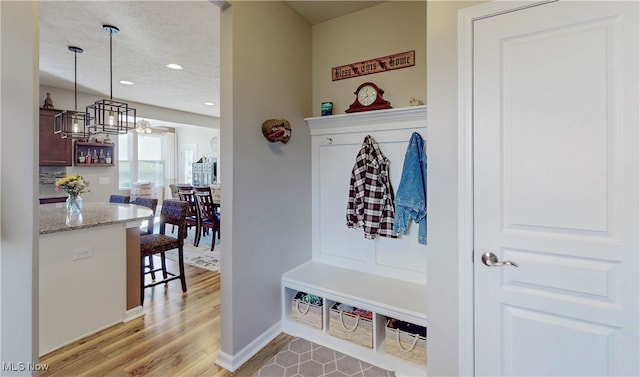 mudroom with a textured ceiling, light hardwood / wood-style flooring, and a notable chandelier