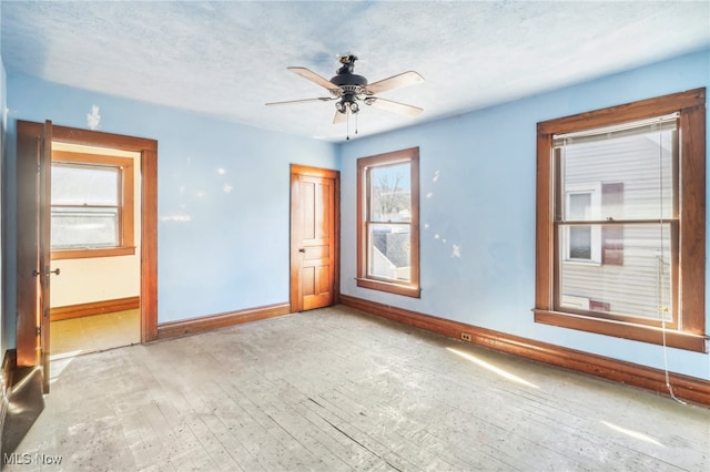 empty room with a textured ceiling, light wood-type flooring, and ceiling fan