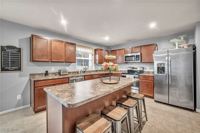 kitchen with stainless steel appliances, sink, a chandelier, a kitchen island, and a breakfast bar area