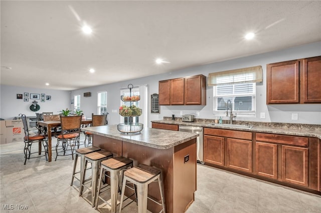 kitchen with stainless steel dishwasher, a kitchen island, sink, and a breakfast bar area