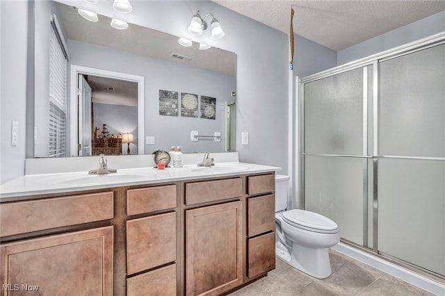 bathroom featuring walk in shower, tile patterned flooring, a textured ceiling, toilet, and vanity