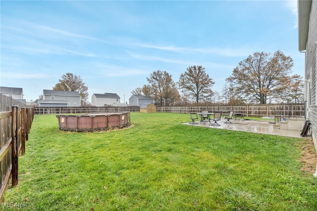 view of yard featuring a patio area, a fenced in pool, and a shed