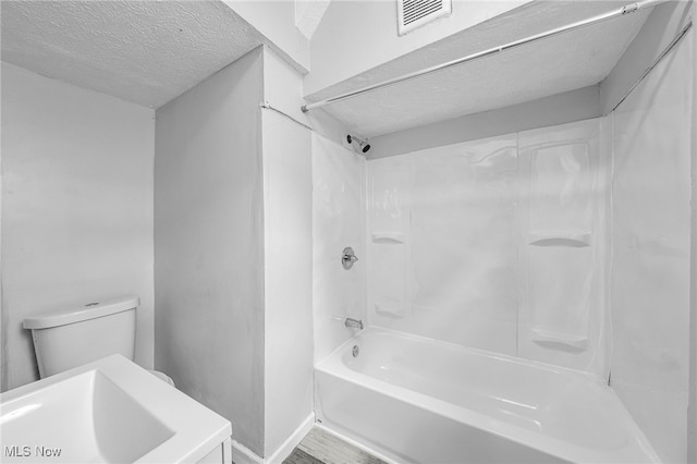 bathroom with toilet, a textured ceiling, visible vents, and bathing tub / shower combination