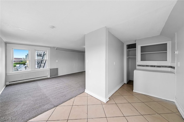 empty room featuring light tile patterned floors, a baseboard radiator, built in shelves, and light colored carpet