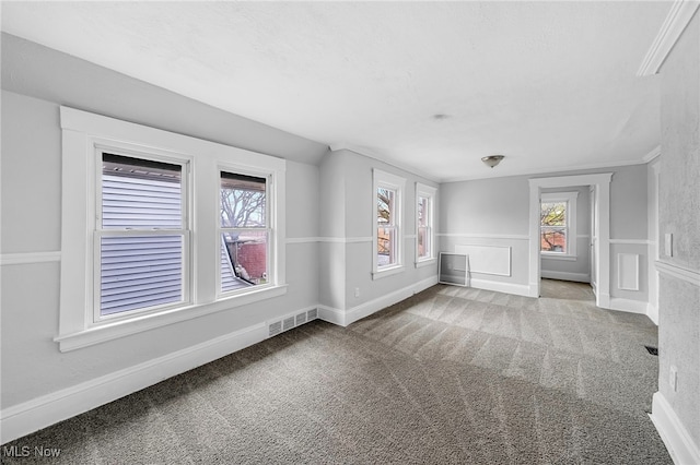 carpeted empty room featuring visible vents, baseboards, and plenty of natural light