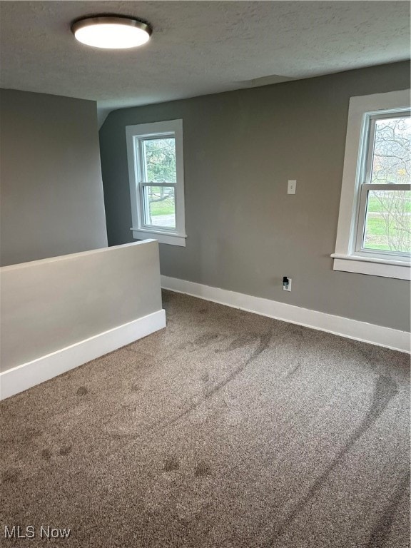 carpeted empty room featuring plenty of natural light and a textured ceiling