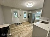 kitchen with gray cabinets, stainless steel fridge, light wood-type flooring, and sink