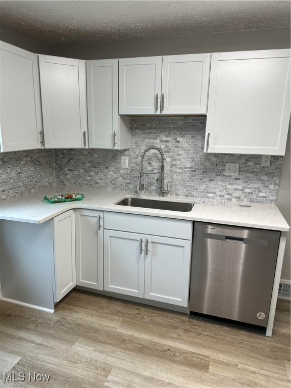 kitchen featuring dishwasher, sink, light hardwood / wood-style flooring, tasteful backsplash, and white cabinetry