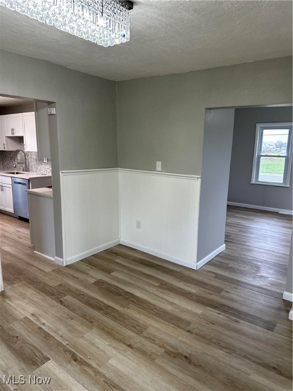 unfurnished dining area featuring sink, a textured ceiling, and hardwood / wood-style flooring