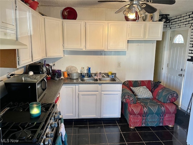 kitchen with a textured ceiling, dark tile patterned floors, sink, range with two ovens, and white cabinets