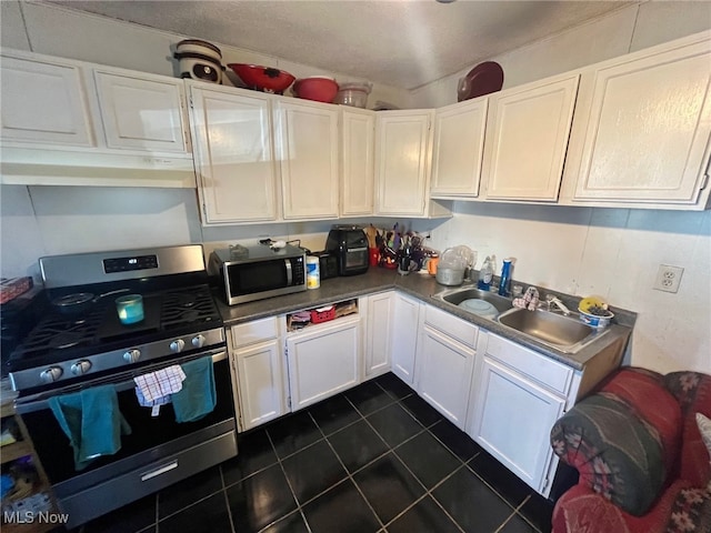 kitchen featuring dark tile patterned floors, sink, white cabinets, and appliances with stainless steel finishes