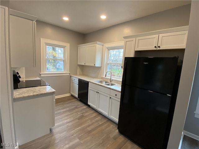 kitchen featuring a wealth of natural light, sink, white cabinets, and black appliances