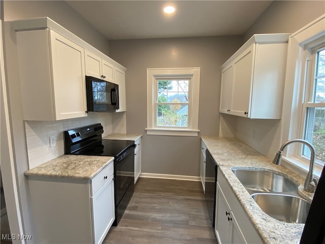 kitchen featuring black appliances, light stone countertops, white cabinetry, and sink