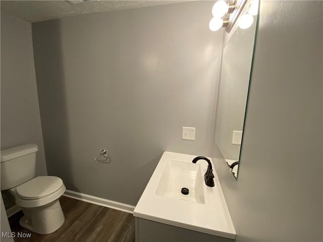 bathroom featuring hardwood / wood-style flooring, vanity, toilet, and a textured ceiling