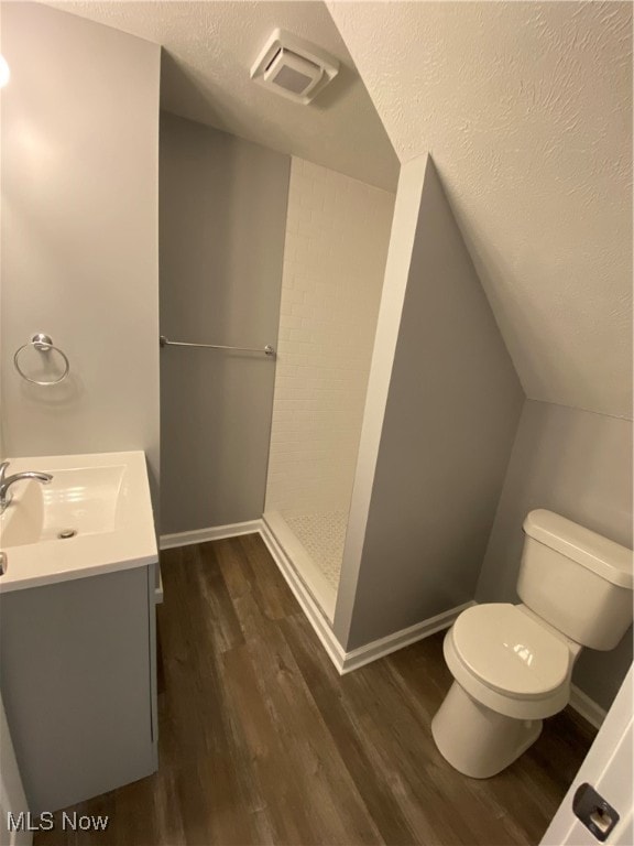 bathroom featuring walk in shower, vanity, a textured ceiling, hardwood / wood-style floors, and toilet