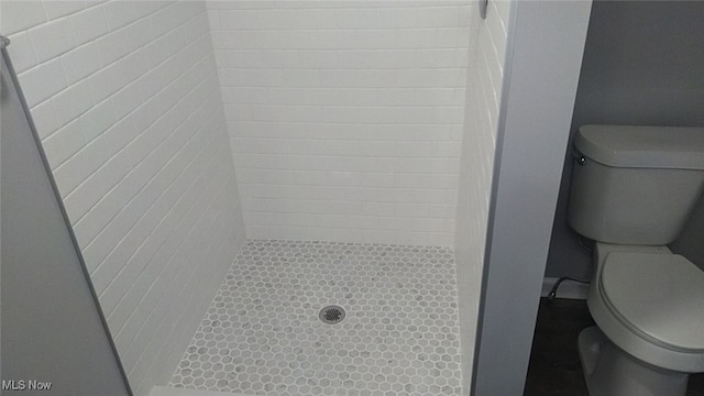 bathroom featuring a tile shower and toilet