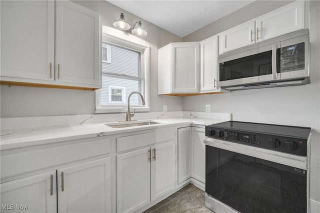 kitchen with light stone countertops, sink, light tile patterned floors, white cabinets, and appliances with stainless steel finishes