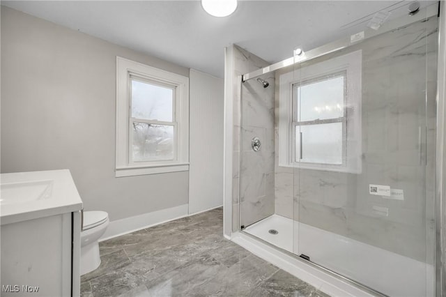 bathroom featuring a shower with door, vanity, and toilet