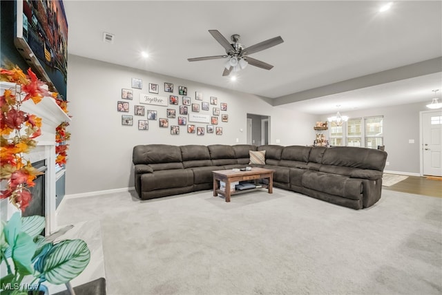 carpeted living room featuring ceiling fan with notable chandelier