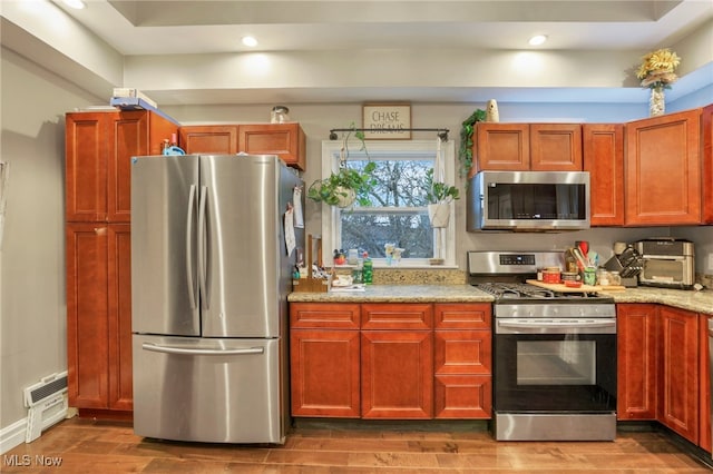 kitchen featuring light stone countertops, appliances with stainless steel finishes, and hardwood / wood-style floors