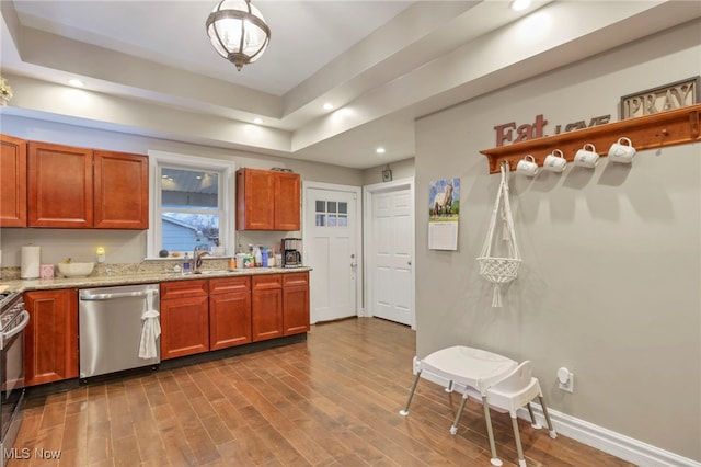 kitchen featuring light stone countertops, sink, stainless steel appliances, pendant lighting, and hardwood / wood-style flooring