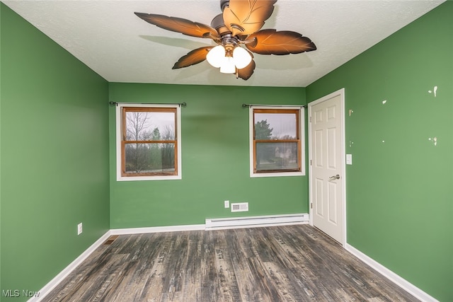 empty room featuring baseboard heating, ceiling fan, dark wood-type flooring, and a textured ceiling