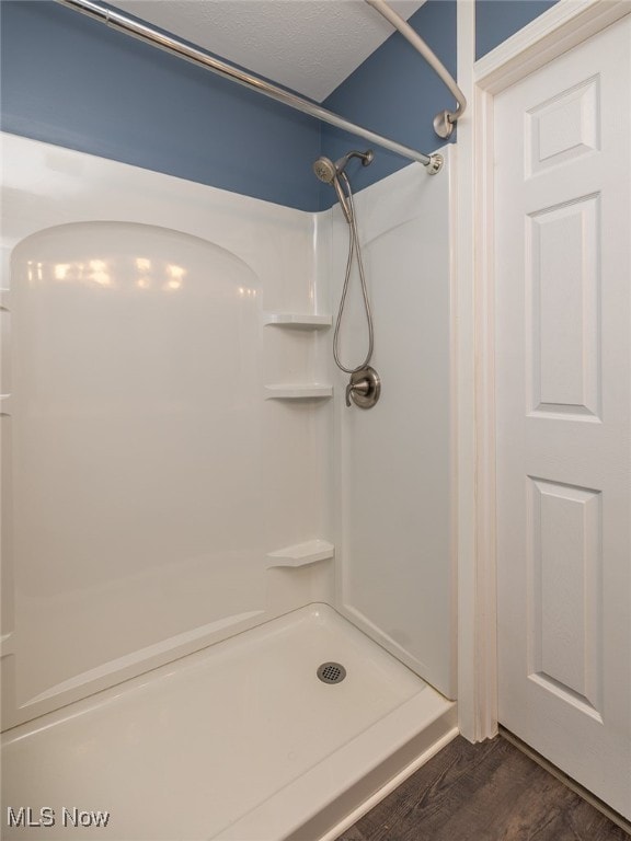 bathroom with hardwood / wood-style floors, walk in shower, and a textured ceiling