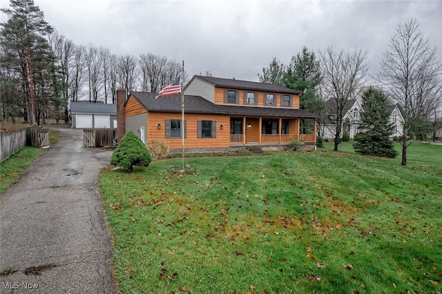 view of front of property with covered porch, a garage, an outbuilding, and a front yard