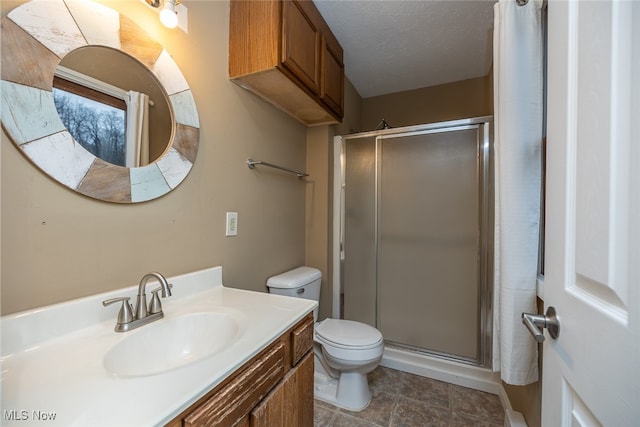 bathroom featuring vanity, a textured ceiling, toilet, and walk in shower