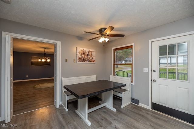 dining space featuring hardwood / wood-style floors, ceiling fan with notable chandelier, and a textured ceiling