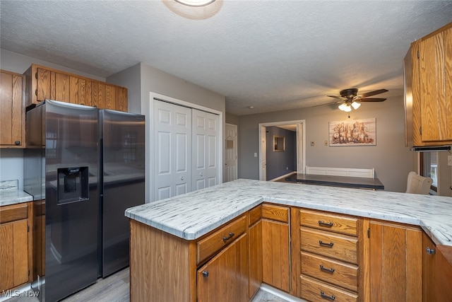 kitchen with stainless steel refrigerator with ice dispenser, ceiling fan, light wood-type flooring, a textured ceiling, and kitchen peninsula