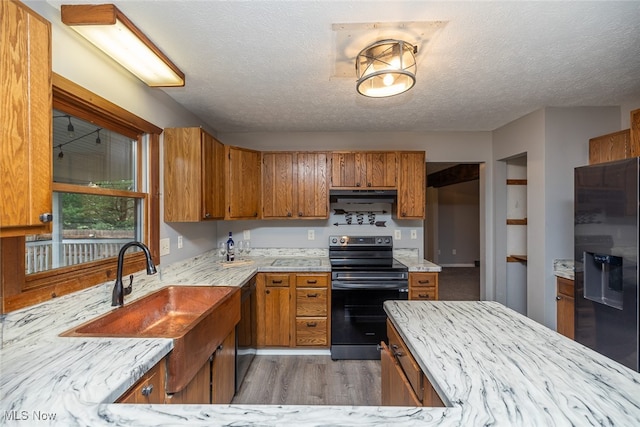 kitchen featuring black appliances, dark hardwood / wood-style floors, sink, and a textured ceiling