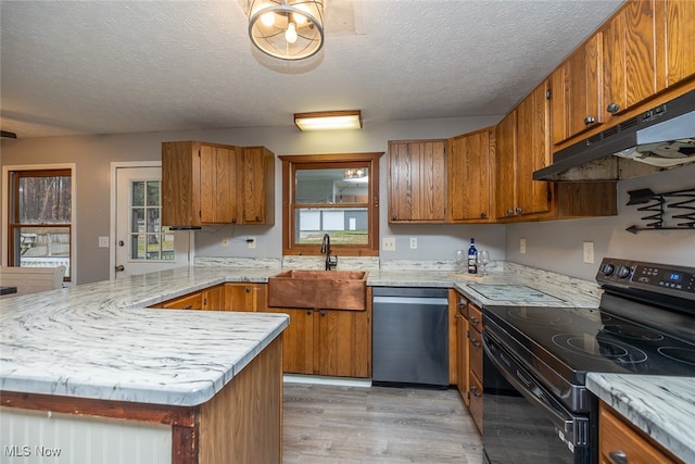 kitchen featuring sink, black range with electric cooktop, stainless steel dishwasher, light hardwood / wood-style floors, and a textured ceiling