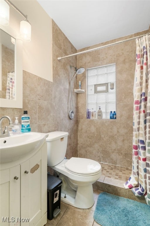 bathroom with toilet, a shower with curtain, tile patterned floors, and tile walls