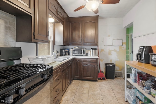 kitchen featuring dark brown cabinets, gas stove, sink, and ceiling fan