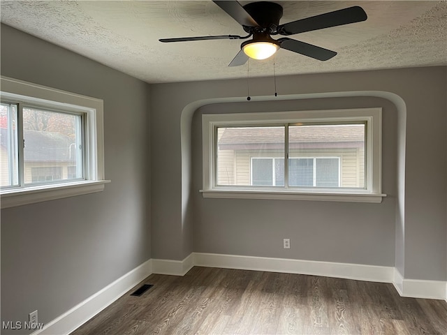 spare room featuring ceiling fan, dark hardwood / wood-style flooring, and a textured ceiling