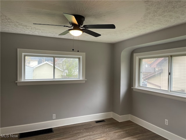 empty room featuring dark hardwood / wood-style floors, a wealth of natural light, and ceiling fan